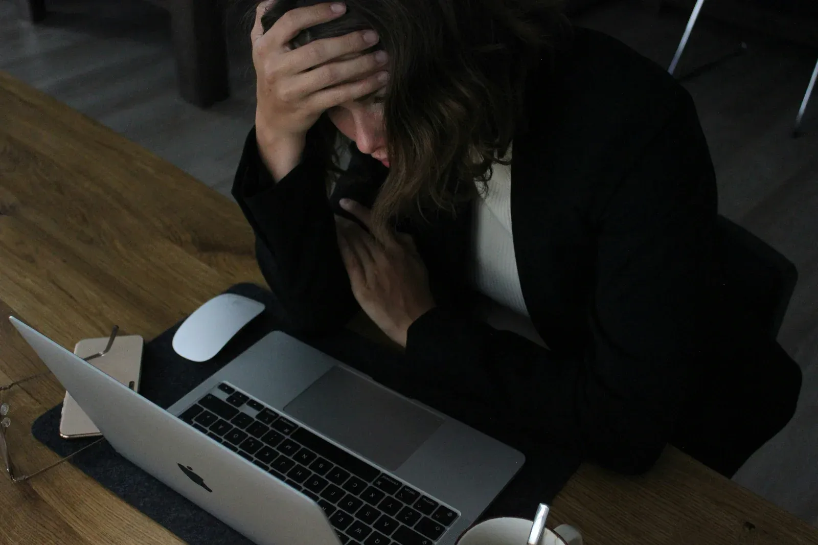 Architektin sitzt erschöpft über ihrem Laptop, den Kopf in die Hand gestützt